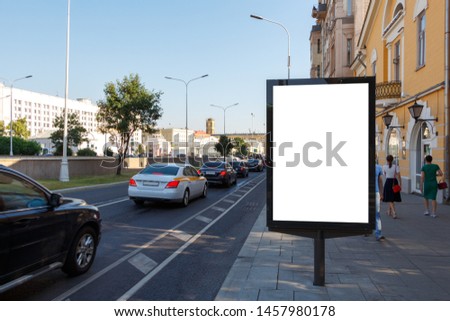 Vertical billboard on the right side of the road on the sidewalk.