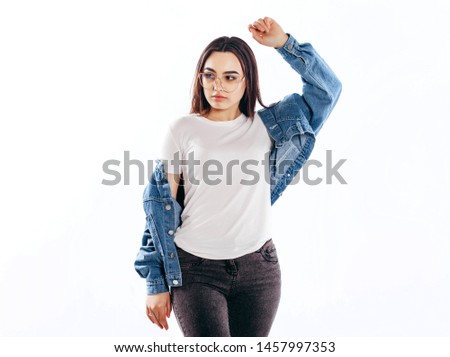 Girl wearing t-shirt with place for logo, glasses and cotton jacket posing in studio