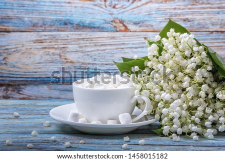 Rural still-life - marshmallows on the background of a bouquet of lilies of the valley, closeup