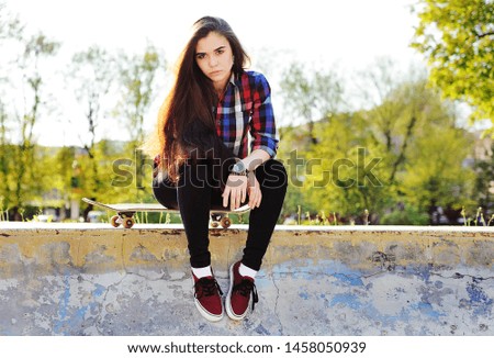 young cute girl with skateboard on the background of the Park