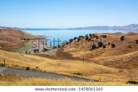 Driving through the golden hills of California the San Luis Reservoir State Recreation area sign and dam on the right side of the road 
