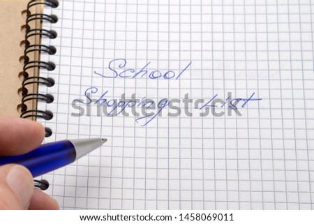 A man writes a blue pen in his notebook. Sign - school shopping list