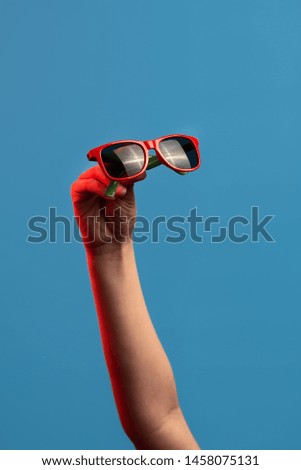 colored sunglasses at arm's length on a blue background