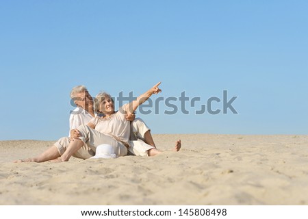 happy mature couple walking barefoot on the sand in the summer