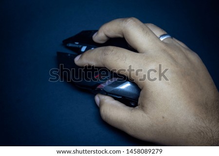 Hand using a wireless gamer mouse on the black surface