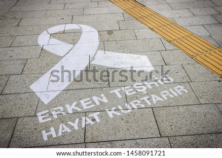 Breast cancer awareness symbol on the sidewalk. "Early diagnosis saves lives" text on the ground in Turkish language.