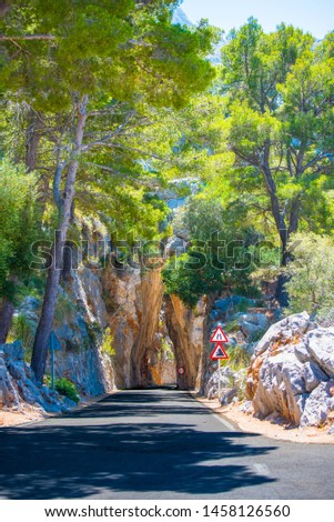 Mountain road between rocks and danger signs. Spain, Mallorca.