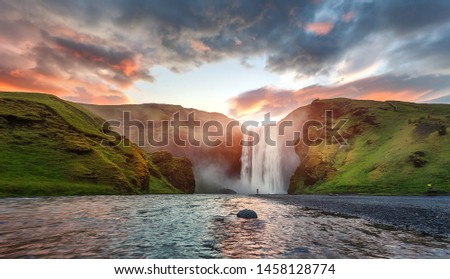 Icelandic Landscape. Classic long exposure view of famous Skogafoss waterfall with colorful sky during sunset. Skoga river, highlands of Iceland, Europe. Popular Travel destinations. Amazing nature