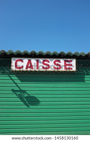 French text: Caisse. English translation: cash register. Sign above a ticket sale hut.