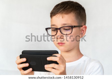 School boy looks handsome smartphone video, in glasses, dressed in white shirt, on white background