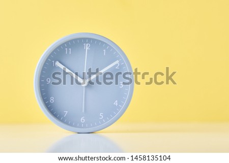 Gray classic alarm clock on pastel yellow background with copy space