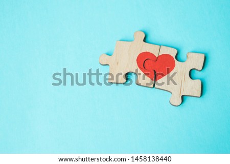 Red heart is drawn on the pieces of the wooden puzzle lying next to each other on blue background. Love concept. St. Valentine day. Copy space.