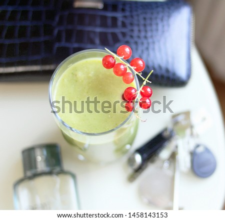 smoothie in a glass decorated with a currant branch, on the background of business items, a breakfast, vegan food, healthy breakfast