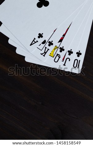playing cards on black background. royal flush in clubs
