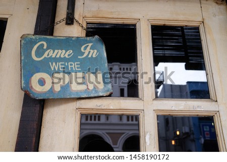 Come In We're Open sign on door of coffee cafe shop