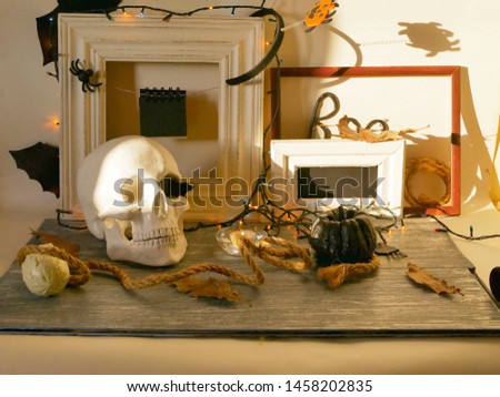 Decorative composition of the skull, pumpkins, lit candles, illumination, leaves and mystical decor on a gray wooden table and a light background, Halloween, autumn, October