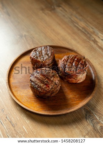 Cooked on grill beef steaks fillet mignon served on wooden plate on brown table with copy space for text menu. Top flat view, overhead.