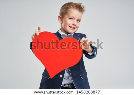Portrait of happy cute little kid holding red heart