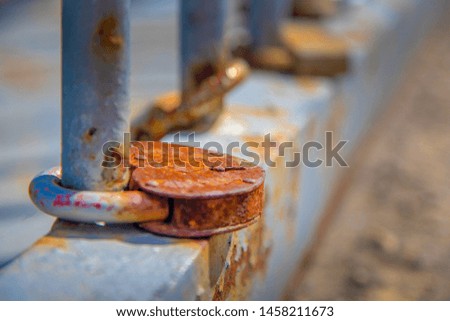 Old rusty lock in the form of a heart chained to the fence.