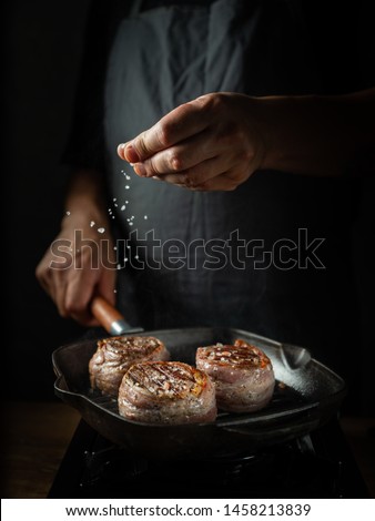 Cooking beef steak on grill pan by chef hands on black background for copy space text restaurant menu,