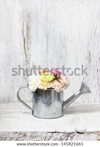 Beautiful carnation flowers in silver watering can, on wooden background
