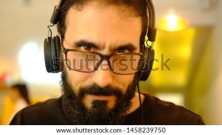 Man  listening to music whit his headphones.  the man is looking forward.