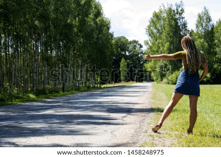 young girl on the edge of a forest road catches a car