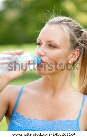 Young Beautiful Woman Drinking Water during Exercising in the Nature