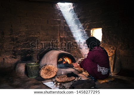 Berber woman making the bread in a mud house in the desert of Morocco