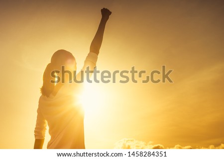 Woman power, victory and winning concept. Woman with fist in the air at sunset.  Royalty-Free Stock Photo #1458284351