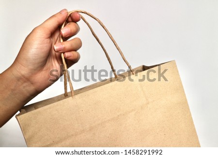 Hand holding recycling paper shopping bag in wall background