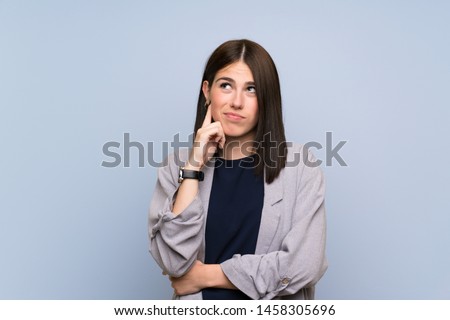 Young woman over isolated blue wall having doubts Royalty-Free Stock Photo #1458305696