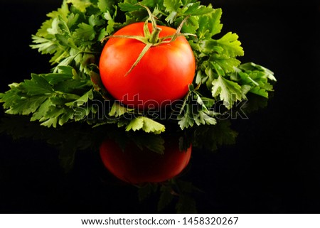 Red mini tomato on black reflective studio background. Isolated black shiny mirror mirrored background for every concept.