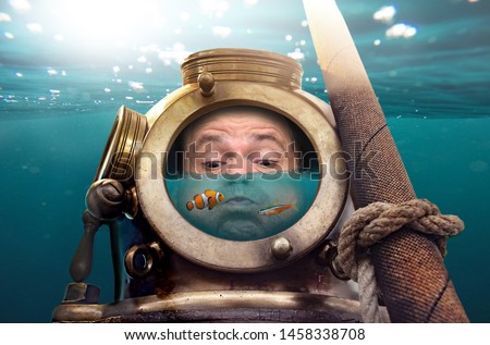 Portrait of man in old diving suit and helmet under water. Funny diver in retro equipment with water and fish inside his helmet .