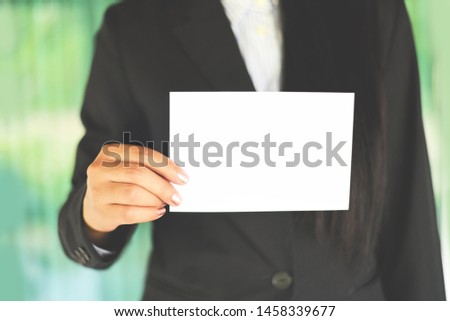 Business woman hand mockup holding blank sheet of paper office working / young woman in suit shows white card Area for advertising white banner , business card or bonus 