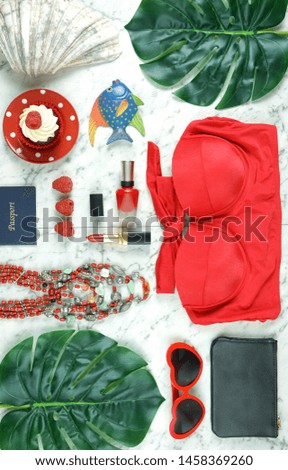 Summer vacation concept flatlay with red feminine accessories on white marble background.