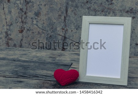 Photo frame with red heart on the retro wooden table with stone wall background. Simple and minimal style for wallpaper. Copy space for text. Love photo concept.