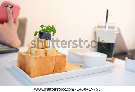 Girl take honey toast picture with salted egg sauce and ice-cream before eat. Set of dessert foods and drink at the cafe
