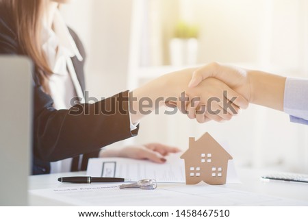 Close-up shots of the model house with groups of people are made of real estate purchase contract is in the background. Royalty-Free Stock Photo #1458467510