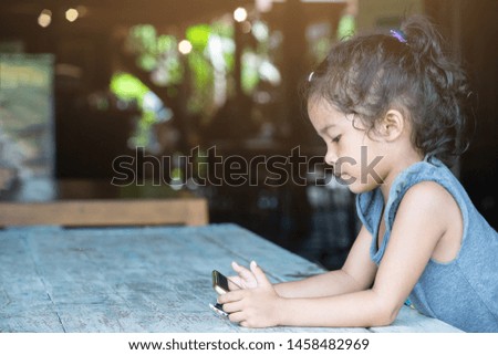Cute Asian Little girl using mobile phone to communication at home