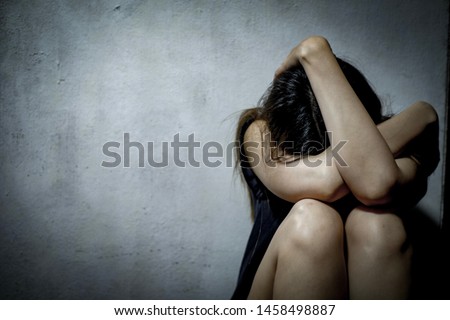 Young woman with depression sitting alone on the floor in the dark room.Teenager girl disappointed and crying. Royalty-Free Stock Photo #1458498887