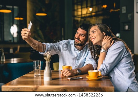 A man taking a picture with his partner at a restaurant