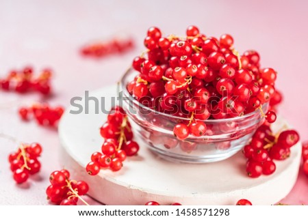 close-up view of fresh ripe red currants in bowl on pink background