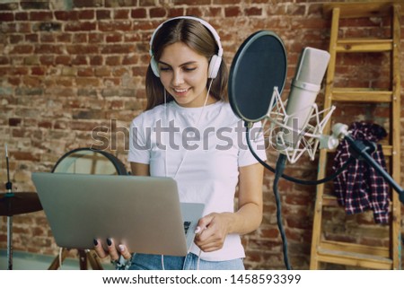 Woman in headphones recording music video blog home lesson, singing or making broadcast internet tutorial while sitting in loft workplace or at home. Concept of hobby, music, art and creation.