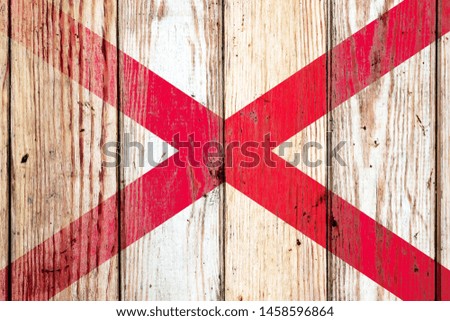 Alabama US state national flag on a gray wooden boards background on the day of independence in different colors of blue red and yellow. Political and religious disputes, customs and delivery.
