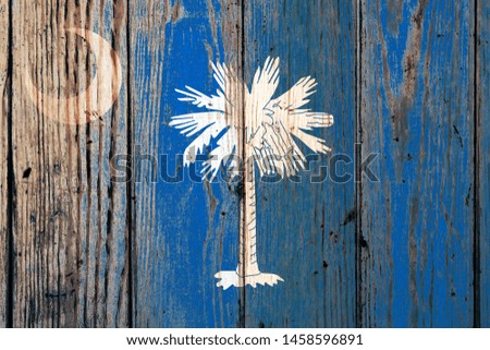 South Carolina US state national flag on a gray wooden boards background on the day of independence in different colors of blue red and yellow. Political and religious disputes, customs and delivery.