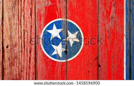 Tennessee US state national flag on a gray wooden boards background on the day of independence in different colors of blue red and yellow. Political and religious disputes, customs and delivery.