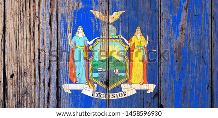 New York US state national flag on a gray wooden boards background on the day of independence in different colors of blue red and yellow. Political and religious disputes, customs and delivery.