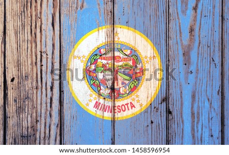 Minnesota US state national flag on a gray wooden boards background on the day of independence in different colors of blue red and yellow. Political and religious disputes, customs and delivery.