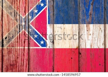 Mississippi US state national flag on a gray wooden boards background on the day of independence in different colors of blue red and yellow. Political and religious disputes, customs and delivery.